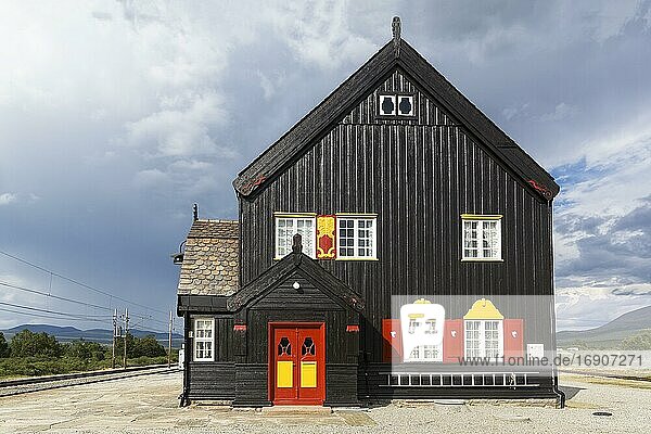Schwarzes Holzhaus mit rotgelber Tür und rotgelben Fensterläden  historischer Bahnhof Fokstua  Dombås  Dombas  Innlandet  Dovrefjell  Norwegen  Europa