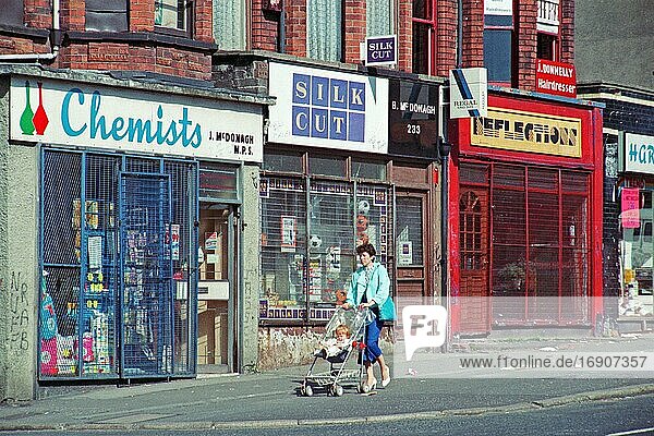 Frau mit Kinderwagen vor vergitterten Geschäften  Falls Road Viertel  historische Aufnahme  08.09.1986  Belfast  Nordirland