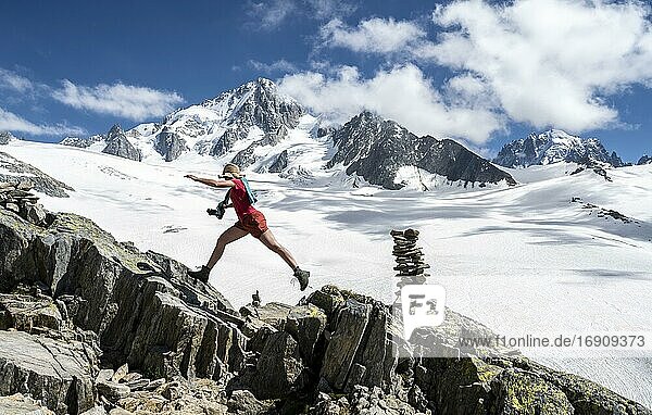 Wanderin springt über Felsen  Glacier du Tour  Gletscher und Berggipfel  Hochalpine Landschaft  links Aiguille du Chardonnet  Chamonix  Haute-Savoie  Frankreich  Europa