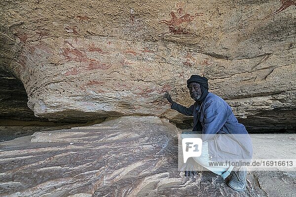 Mann weist auf eine Felsmalerei im Unesco-Welterbe hin  Ennedi Massiv  Tschad  Afrika