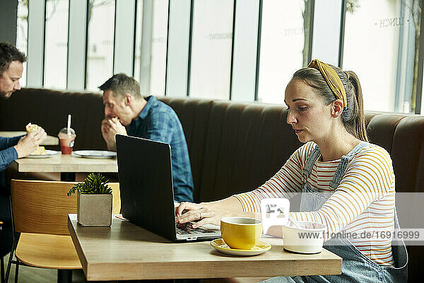 Frau in einem Café sitzend mit einem Laptop