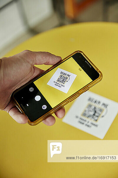 Eine Person  die ein Smartphone benutzt  fotografiert einen Track-and-Trace-QR-Code