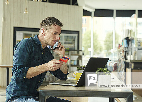 Man seated in a cafe  working on a laptop