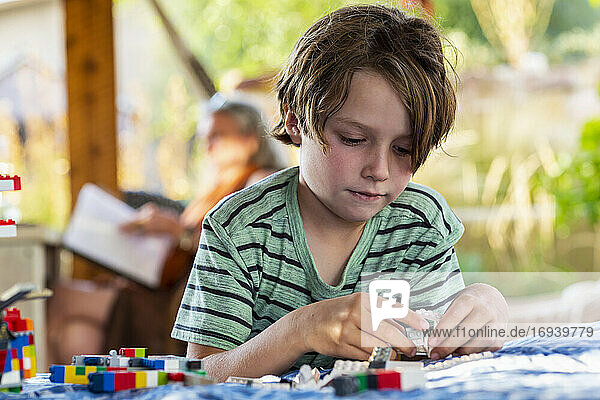 7 year old boy playing with building blocks on a terrace