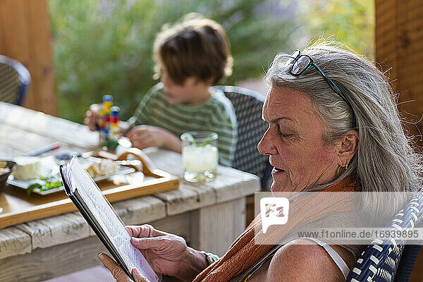 Frau liest Akte draußen auf Terrasse bei Sonnenuntergang.