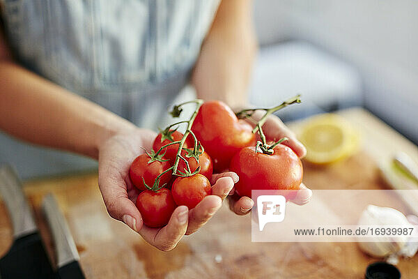 Frau hält unterschiedlich große Bio-Tomaten in der Küche