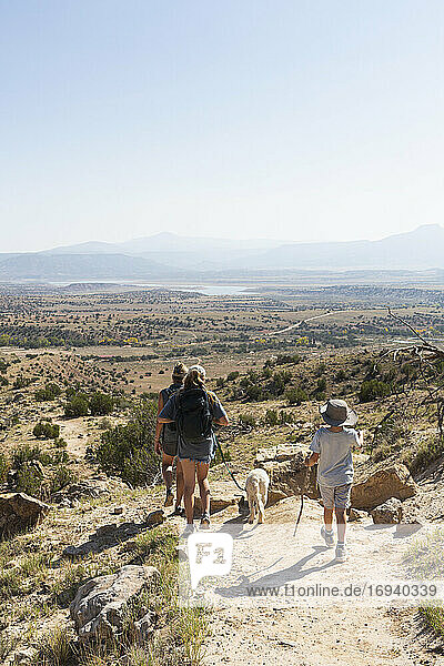 Three people  family hiking on a trail through a protected canyon landscape