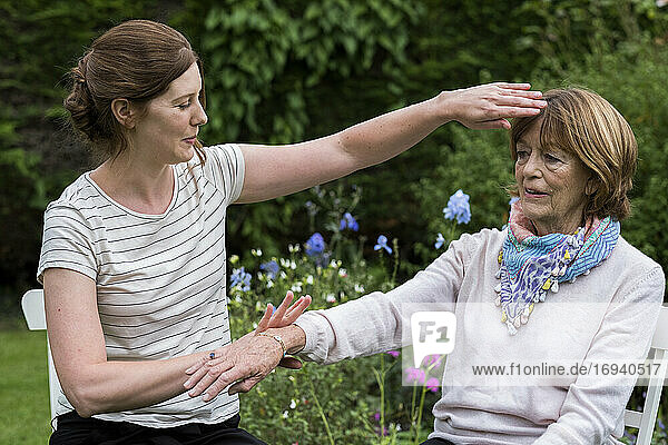 Reiki therapist with a client in a therapy session touching meridian points on the body.