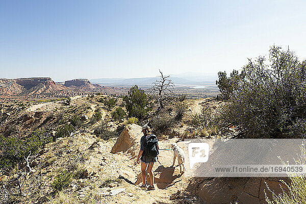 Teenager-Mädchen und ihr Retriever-Hund wandern auf einem Pfad durch eine geschützte Canyon-Landschaft
