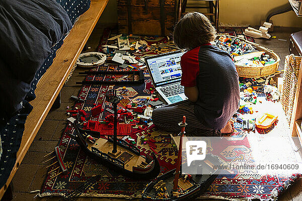 Junger Junge spielt in seinem Zimmer  schaut auf Laptop