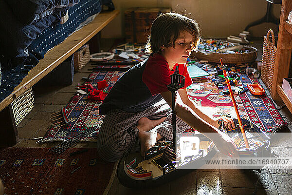 Draufsicht auf einen kleinen Jungen in seinem Zimmer  der mit seinen Spielsachen spielt