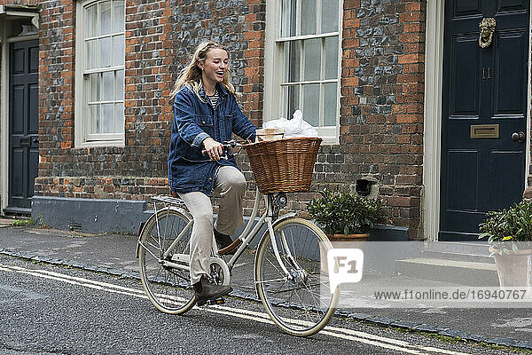 Junge blonde Frau auf dem Fahrrad in einer Dorfstraße.