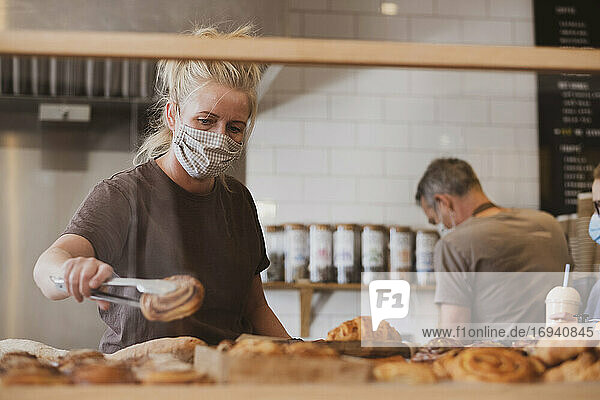 Kellnerin mit Gesichtsmaske bei der Arbeit in einem Cafe.