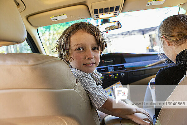 Young boy looking at camera in parked car.