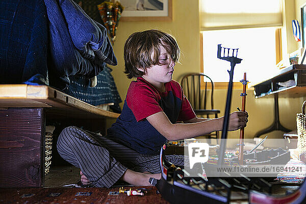 7 Jahre alter Junge spielt mit seinem Spielzeug in seinem Zimmer