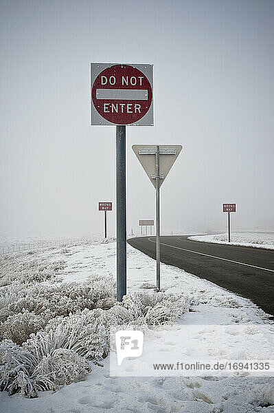 Verkehrszeichen auf der Straße in winterlicher Landschaft.