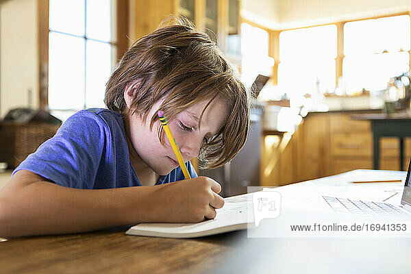 Young boy at home writing and drawing in his drawing pad