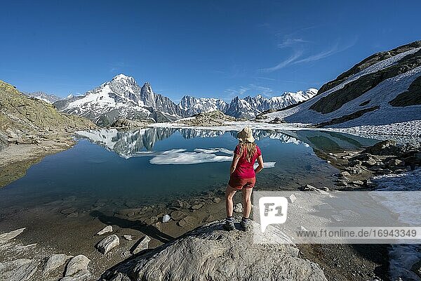 Young woman in front of mountain panorama  reflection in Lac Blanc  mountain peaks  Grandes Jorasses and Mont Blanc massif  Chamonix-Mont-Blanc  Haute-Savoie  France  Europe