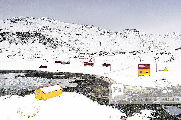 Bunte Holzhäuser im Fischerdorf Breivikbotn mit Schnee bedeckt  Insel Soroya  Hasvik  Troms og Finnmark  Arktis  Norwegen  Skandinavien  Europa