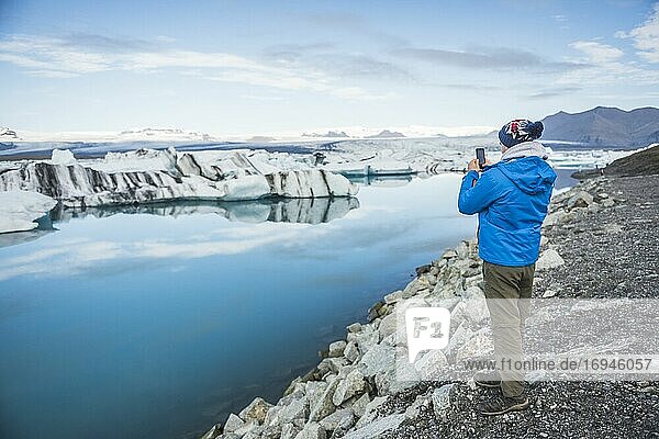 Tourist an der Jokulsarlon Gletscherlagune  einem mit Eisbergen gefüllten Gletschersee im Südosten Islands
