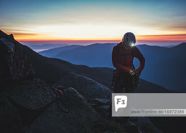 Frau sortiert vor Sonnenaufgang Felsenausrüstung in den Bergen