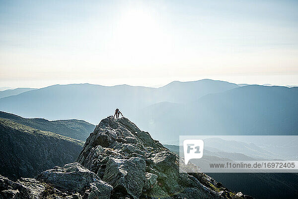 Frau klettert morgens in den Bergen über den Gipfel