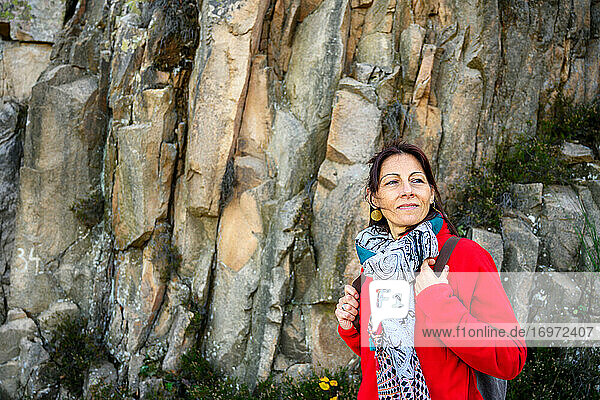 Laughing hiker woman with scarf and backpack  against stone formation