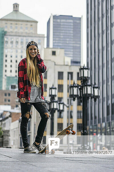 Weiblicher Millennial in städtischem Gebiet mit Skateboard bereit zu rollen ar