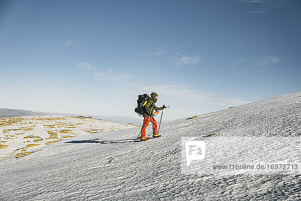 Young male hiking uphill on snow against clear blue sky  Gredos  Avila  Spain