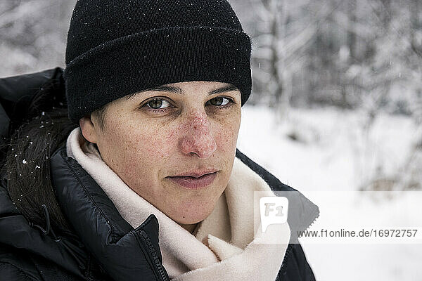 Ruhige Frau in warmer Kleidung im Winterwald an einem verschneiten Tag im Wald
