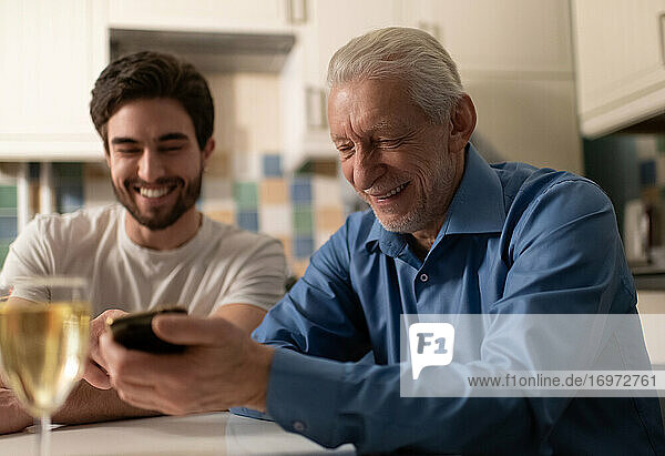 Cheerful mature father showing photos to son