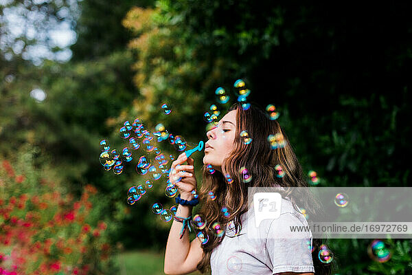 Teenager bläst Seifenblasen im Freien mit schillernden Farben und Aktivität