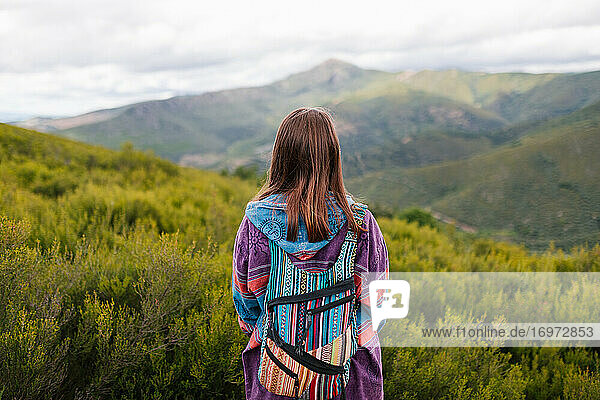 Junge Frau mit alternativer Kleidung Blick auf einen großen grünen Berg