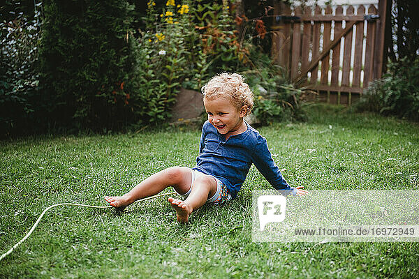 Kleiner Junge spielt in baykyard im Sommer mit Spaß sitzen auf Gras