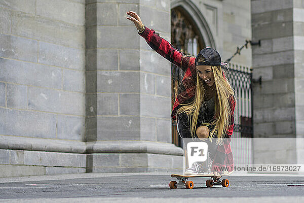 Weibliche Skateboarderin balanciert auf einem Skateboard und rollt durch die Gegend