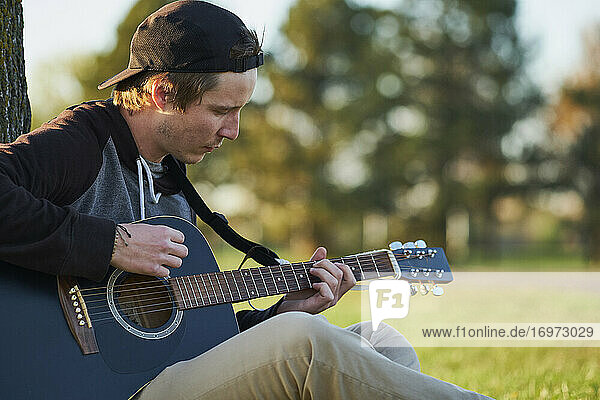 Young musician outside playing guitar