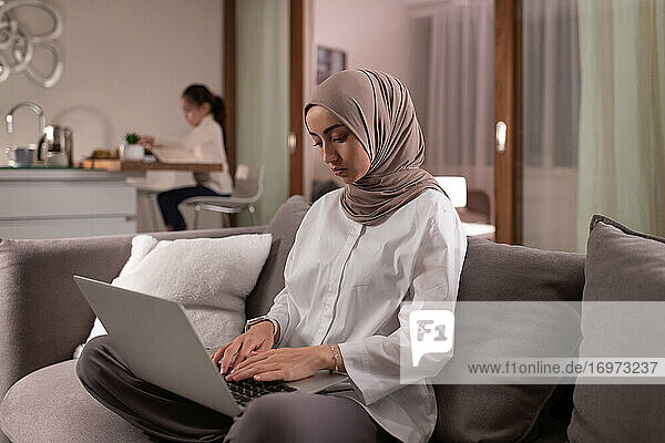 Muslimische Mutter benutzt Laptop für die Arbeit
