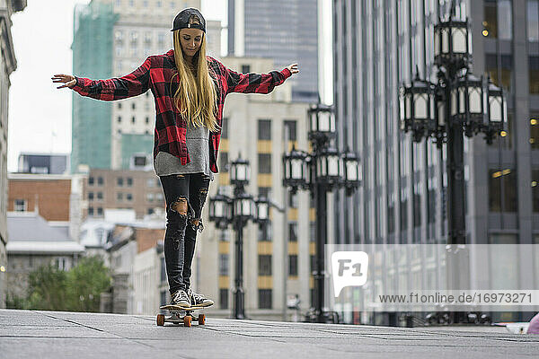 Weibliche Skateboarderin balanciert auf einem Skateboard in einem städtischen Gebiet