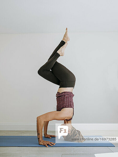 Fit sportlich muskulöse Frau tut Kopfstand Yoga-Pose drinnen
