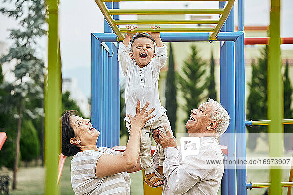little boy having fun with his grandparents in the park