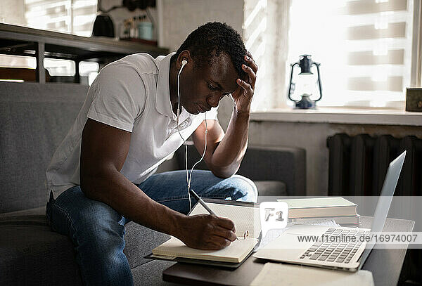Ein afroamerikanischer Student macht sich Notizen während des Fernunterrichts