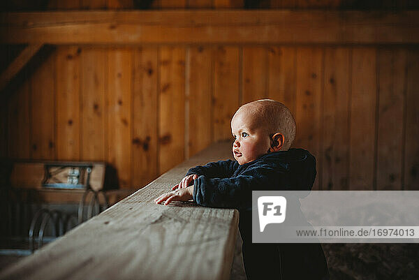 Seite Profil Porträt der entzückenden Baby-Junge mit Holzwänden Bauernhaus