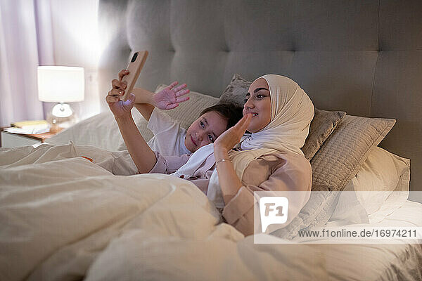 Muslim mother and daughter greeting father online