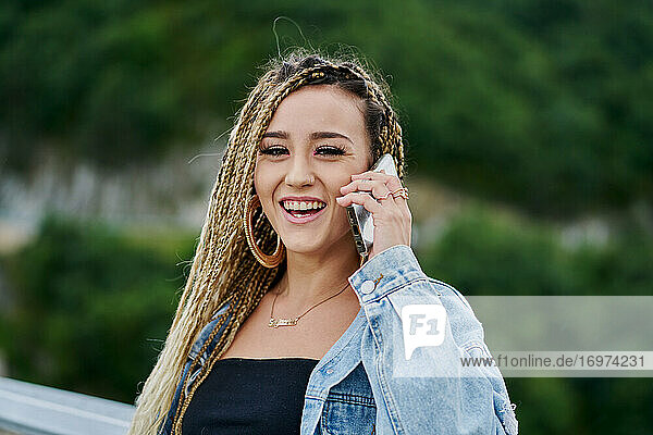 Close-up portrait of a young woman with braided blonde hair talking on her smartphone
