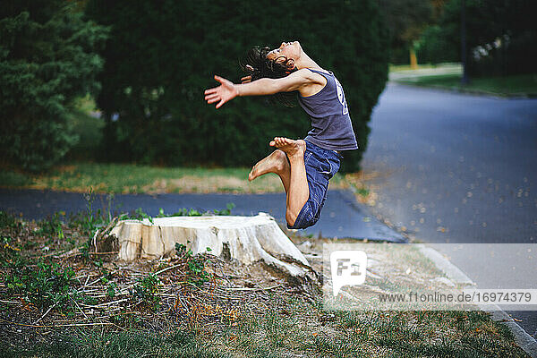 ein anmutiger  athletischer  barfuß laufender Junge springt im Sommer hoch in die Luft