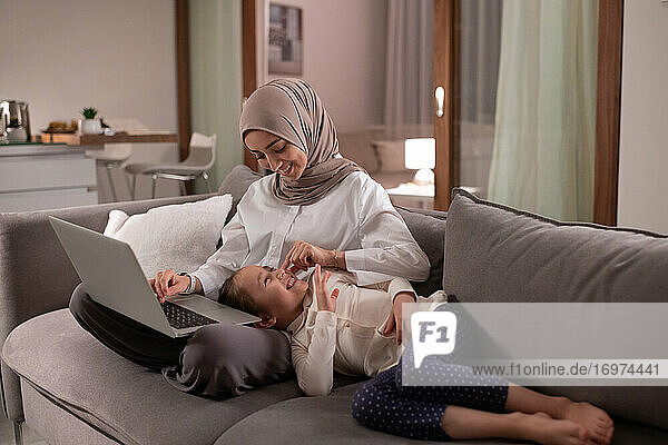 Happy Muslim mother playing with daughter during work