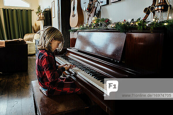 Kleiner Junge spielt Klavier mit Weihnachtsschmuck