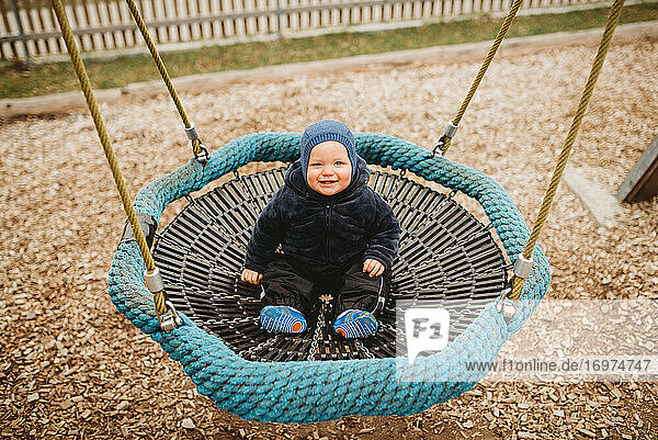 Cute Baby im Freien Spielplatz im Winter auf ein Nest Hängematte