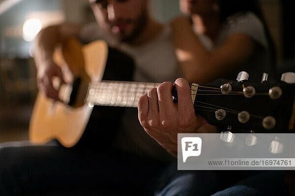 Anonymer Mann spielt Gitarre in der Nähe seiner Freundin