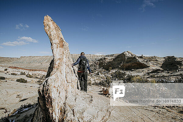 woman hikes along sharp rock outcrop Capital Reef National Park  Utah